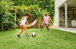 grandmother and grandson playing soccer in backyard