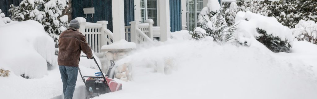 man using snowblower in front of house