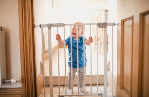 baby holding bars to safety gate
