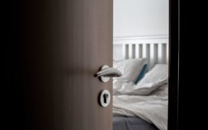 ajar door to bedroom with bed in the background