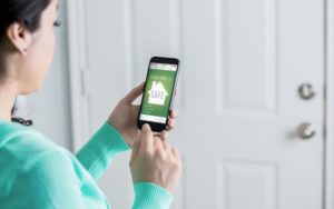 female homeowner uses smartphone to check home security