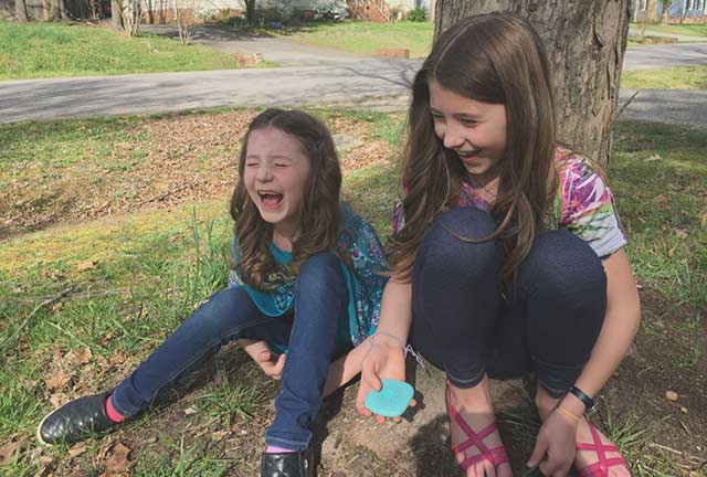 two girls laugh under a tree
