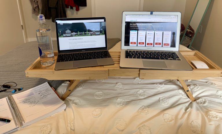 Bathtub laptop caddy with two laptops on a bed