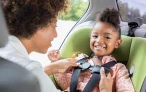 car seat with mother buckling in young daughter
