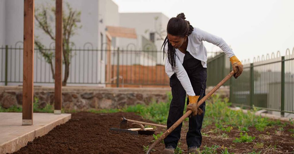woman raking dirt in a garden