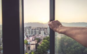 man's hand opening window to cityscape