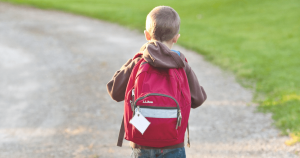 Child walking to school with red backpack