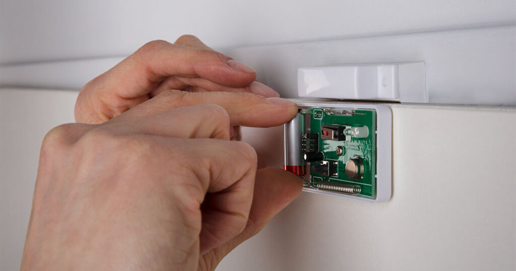 close up of someone changing a battery in a door sensor