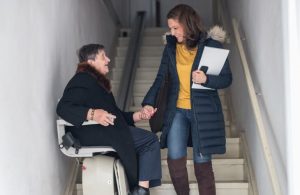 woman in stair lift and woman walking on stairs