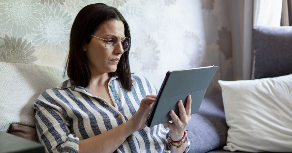 woman concentrating on tablet sitting on couch