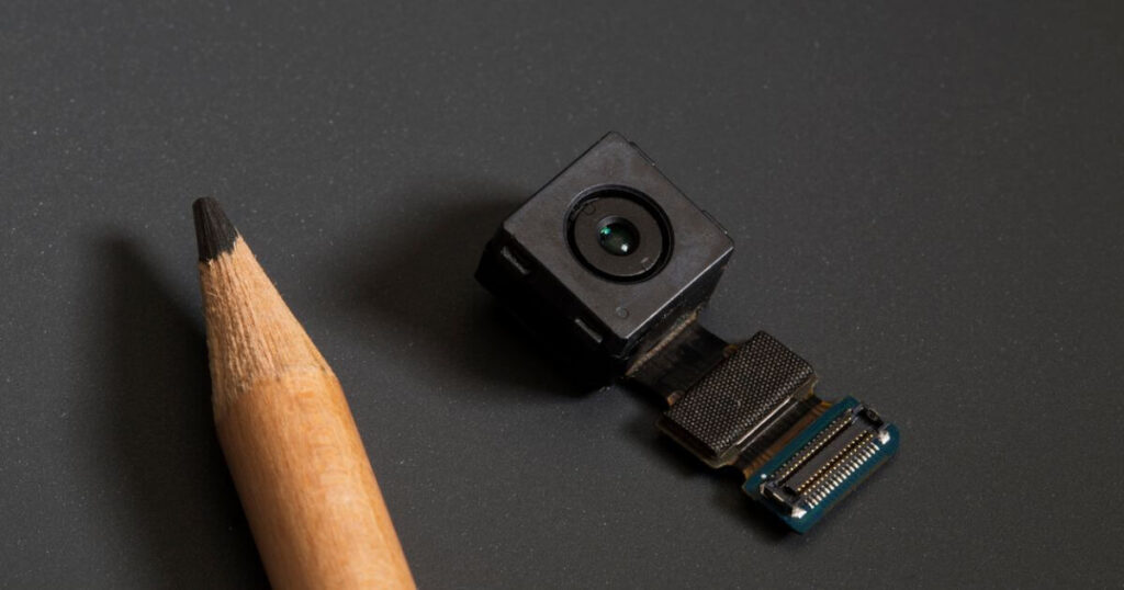 tiny camera next to the tip of a pencil for scale