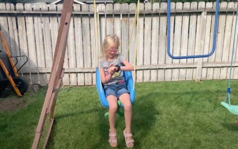 Little girl on swing using TickTalk 4 smartwatch