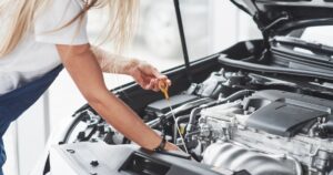 woman checking oil under hood of car