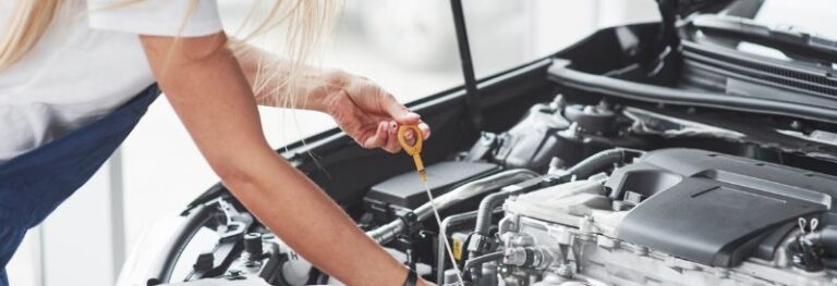 woman checking oil under hood of car