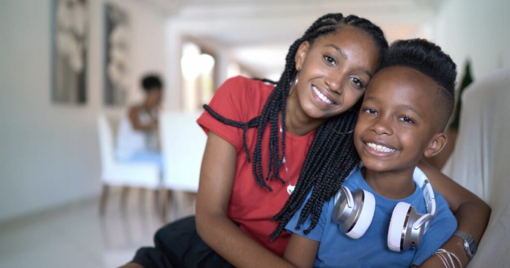 siblings smiling with their arms around each others shoulders