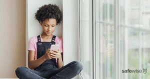 young-girl-using-cell-phone-by-window
