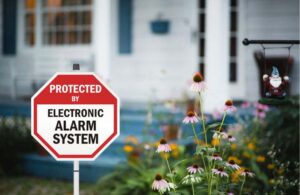 electronic alarm system sign in front of home