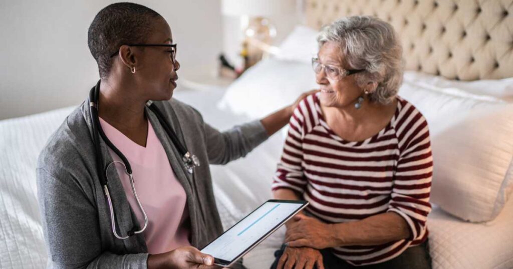 Health care professional talking to a senior woman in the bedroom