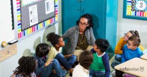 Teacher and children doing school safety drill, lockdown A multiracial group of seven school children and their teacher doing a practice drill, sheltering in place, sitting on the floor in a corner of their classroom. Practice Drill Stock Photo