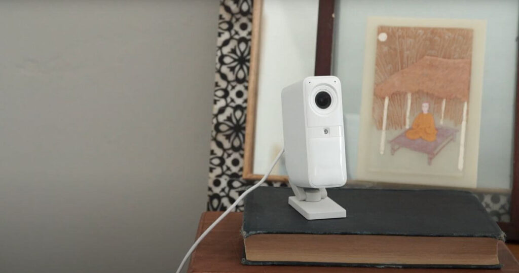 SimpliSafe Smart Alarm camera on a shelf in front artwork.