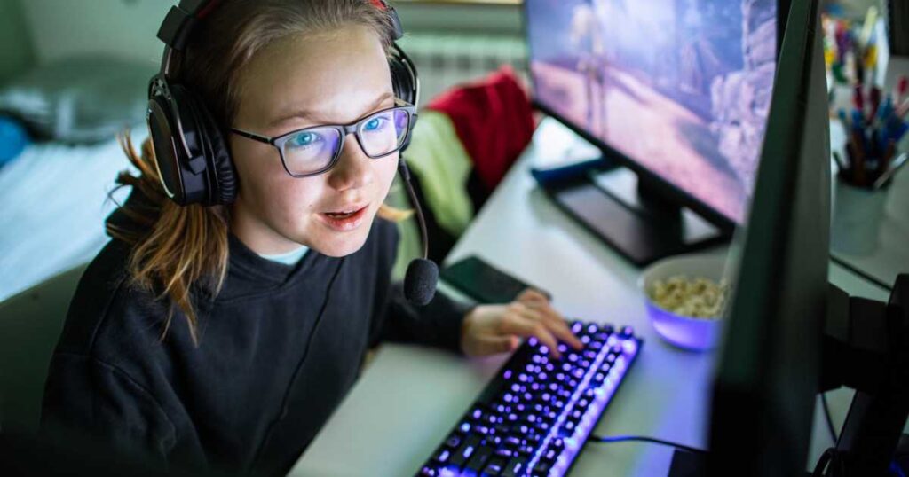 Young girl playing video games on her desktop computer stock photo