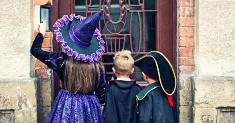 Halloween kids ringing the doorbell of an old scary house. The boys aged 6 are dressed up as skeleton pirate and vampire. The girl aged 9 is dressed up as witch.
