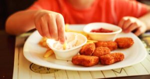 Child eating french fries with chicken nuggets