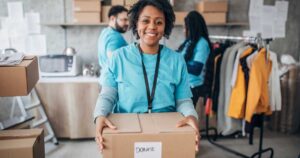 Multi-ethnic group of people, diverse people volunteers packing donation boxes in charity food bank.