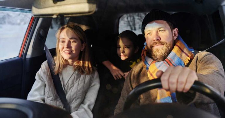 Happy family sitting in car with their child while dad driving, they travelling during winter holidays