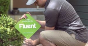 Man installing Fluent home security sign in a front yard