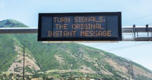 "TURN SIGNALS, THE ORIGINAL INSTANT MESSAGE" whimsical humorous reminder caution message on an expressway overhead LCD road sign in Utah, USA.