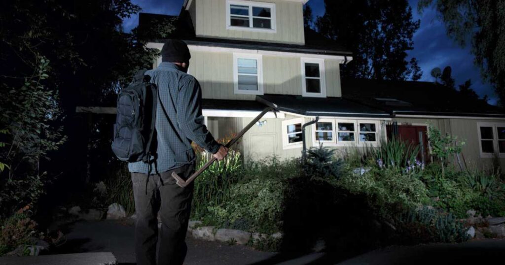 Burglar approaching a home at night stock photo