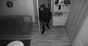 Burlgar entering home in black and white camera footage