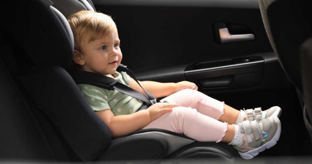 little girl sitting in child safety seat inside car