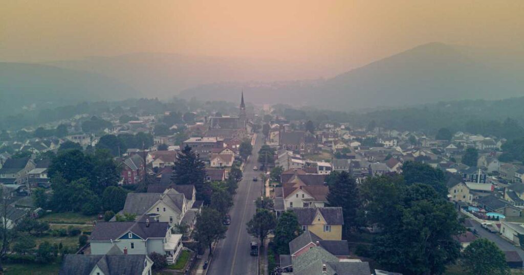 Residential townscape amidst the smog. Sunset sky veils mountains in the distant in Jim Thorpe, Appalachian Mountains, Poconos, PA. Aerial view stock photo