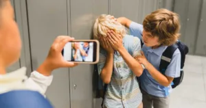 Boys filming on the phone bullying their classmate in school hall.