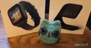 The SafeWise mascot in front of the COSMO JrTrack 5 watch and charging stand boxes.