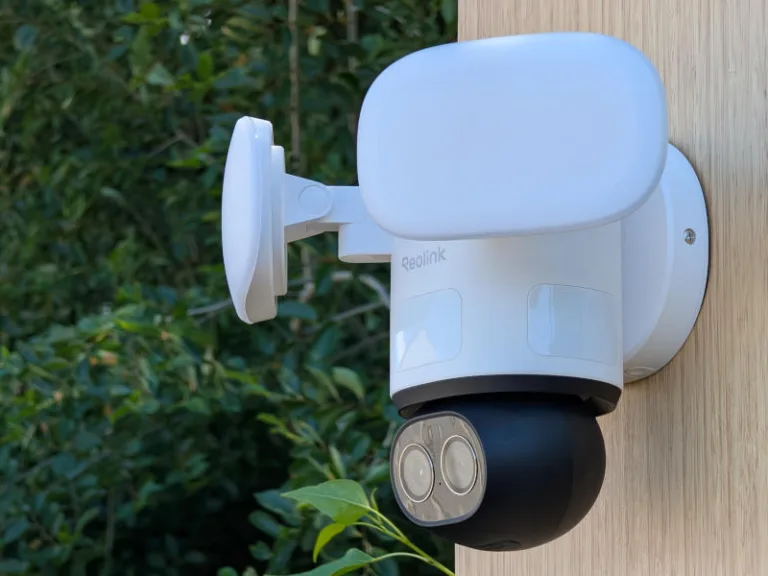 reolink trackflex floodlight wifi security camera outside on wall with tree in background
