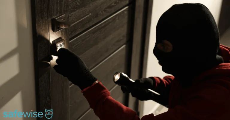 Burglar trying to break in while holding a flashlight
