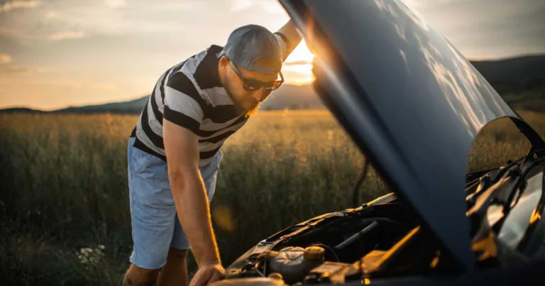 Man fixing car on a country road in sunset