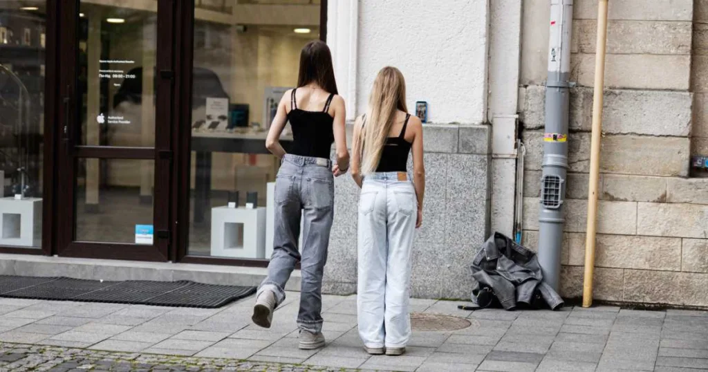 Two teen girls friends dancing for TikTok together in casual outfits outside a modern storefront