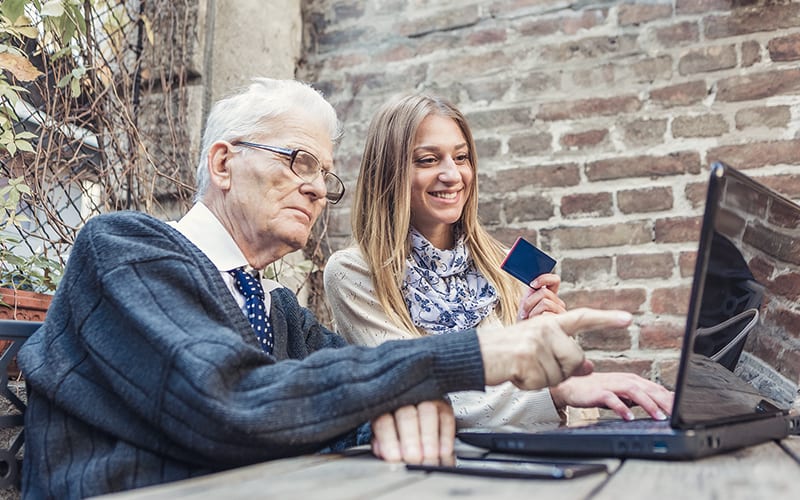 a senior citizen using a computer with young woman