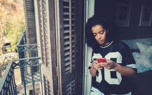 teenager on phone near balcony of house