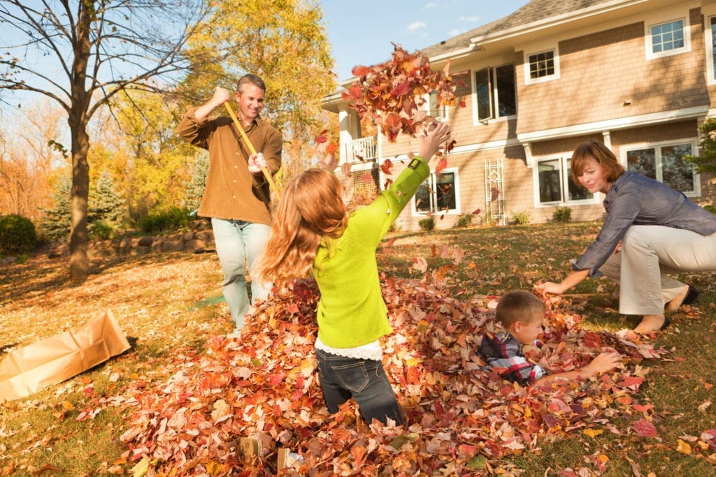 family playing in the leaves in fall